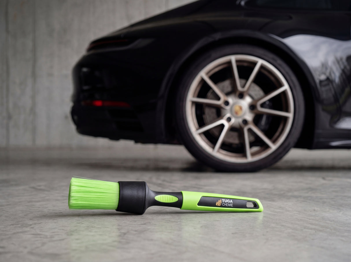 TUGA Chemie Detailing-Felgenpinsel mit grünem Kunststoffgriff und grünen Synthetik-Borsten auf Betonvorplatz vor Porsche 911 Alufelge