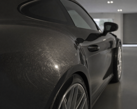 Detailing1 Lackinspektion: feine Swirls auf dem dunklen Lack eines Porsche 911 GT3 RS werden unter Streiflicht in der Halle sichtbar