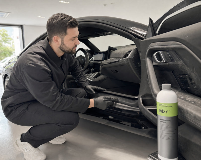 Detailing1 Koch-Chemie Mzr — verstaubtes Cockpit eines schwarzen BMW M2 vor der Innenraumreinigung