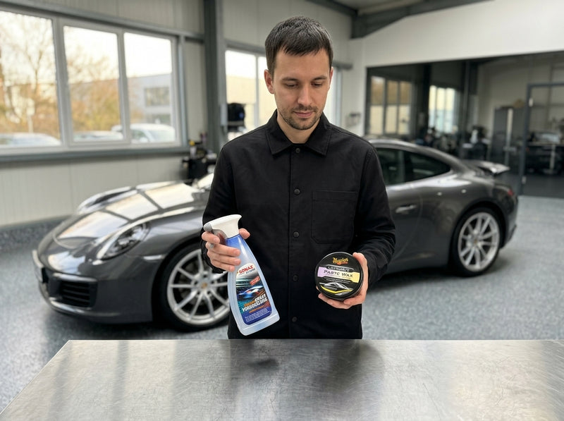 Daniel haelt Spruehversiegelung und Hartwachs nebeneinander vor einem dunklen Sportwagen